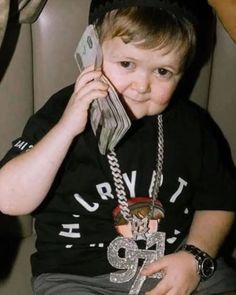 a young boy talking on a cell phone while wearing a hat and holding money in his hand