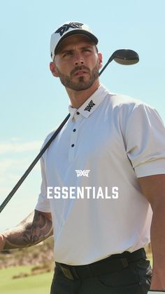 a man holding a golf club and wearing a white shirt with the words essentials on it