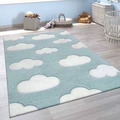 a baby's room with blue walls and white clouds on the rug in it