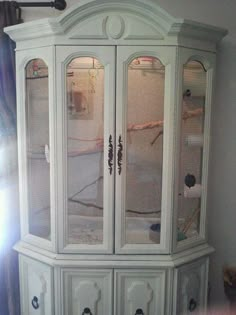 a white china cabinet with glass doors