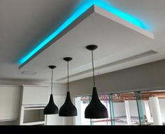 three lights hanging from the ceiling in a room with white walls and cabinets, along with black lamps