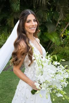 a beautiful woman in a wedding dress holding a bouquet of flowers and posing for the camera