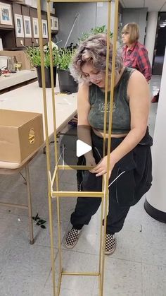 a woman sitting on top of a metal shelf next to a potted plant in a room