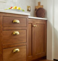 a kitchen with wooden cabinets and white counter tops, gold pulls on the handles that are brass