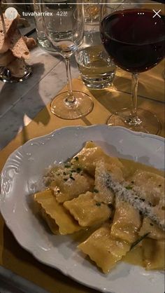 a plate of ravioli with parmesan cheese and wine