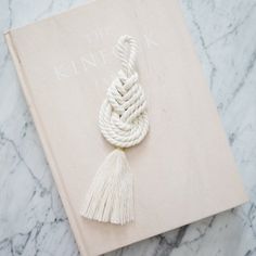 a book with a tassel on top of it sitting on a marble table next to a white rope