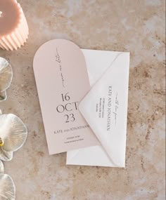 the wedding stationery is laid out next to some cupcakes and flower petals