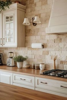 a kitchen with white cabinets and wooden counter tops next to a stove top oven in front of a brick wall