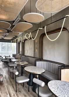 the interior of a restaurant with tables, chairs and lights hanging from the ceiling above them