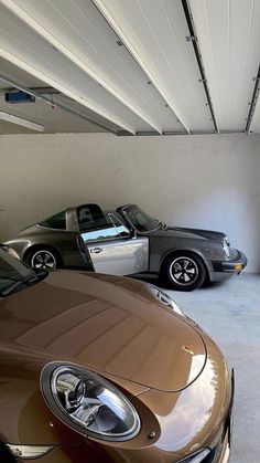 two cars are parked in a garage next to each other, one is brown and the other is black