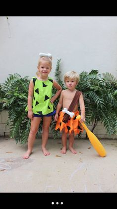 two young children standing next to each other in swimsuits and holding paddles