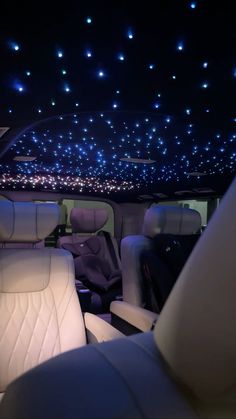 the interior of a car with blue lights on the ceiling and white leather seats in it