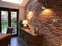 a brick wall with two lamps on it and a table in front of the door