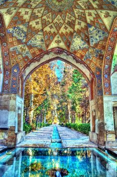 an ornate archway with a pool in the middle and trees around it on either side