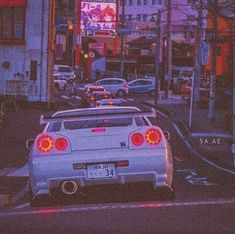 the back end of a white car parked in front of a tall building on a city street