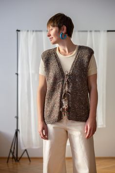 "An absolutely beautiful handmade wool knit sweater vest made from speckled taupe brown yarn. It features V-neck and tie closure at front with colourful bead detail. It is hand knitted by my wonderful mother who creates beautiful things - more to come soon! Material: feels like wool or a wool blend (not itchy! no tag) Condition: new, made from used yarn of great condition Size: best fits size L (no size tag) Please compare measurements with a similar piece of your own before purchase. Measuremen Fall Knitted Brown Sweater Vest, Knitted Waistcoat Outfit, Brown V-neck Knit Sweater Vest, Brown Knitted Sweater Vest For Layering, Brown Knit V-neck Sweater Vest, Brown Knit V-neck Vest, Brown Knit Vest For Layering, Brown Knitted Sweater Vest, Brown Knit Sweater Vest