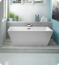 a white bath tub sitting next to a window in a blue and white bathroom with potted plants