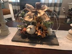 an arrangement of pumpkins and sunflowers in a glass bowl on a table