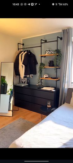 a bedroom with a bed, mirror and clothes on the rack in front of it