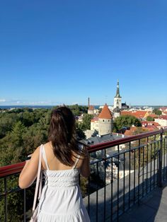 a woman standing on top of a balcony looking at the city