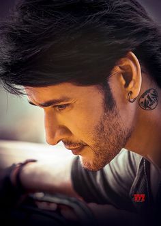 a man with a tattoo on his neck looking down at his cell phone while wearing earrings