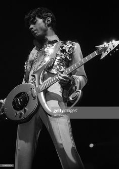 a man with a guitar in his hand and wearing a suit that has flowers on it