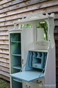 an old dresser is painted white and has blue paint on the top, and it's doors are open