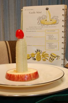 an apple and banana on a plate with a book in the background