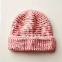 a pink knitted beanie sitting on top of a white table next to a wall