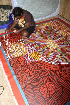 a person sitting on the floor with a painting