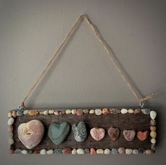 a wooden sign that has some rocks in it and is hanging on the wall with rope