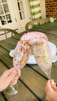 two people toasting glasses with sprinkles on top of them at a picnic table