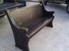 a metal park bench sitting on top of a cement floor next to a black truck