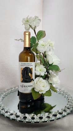 This beautiful, white rose bottle bouquet is the perfect accent for your wedding decor. This floral wine bottle bouquet is perfect for your wedding reception or bridal shower. This beautiful bouquet has a clip filled with a wide variety of high quality roses and cherry blossoms. This clip can be attached to a multitude of other items for the non-drinkers in your life. For just a few ideas, attach this beautiful floral arrangement to a specialty olive oil, bath soap, battery operated candle, or e Wine Bottle Centerpieces For Wedding Diy, Wine Bottle Centerpieces For Wedding, Wine Bottle Bouquet, Rose Wine Bottle, Wine Bottle Wedding Centerpieces, Bottle Bouquet, Wedding Reception Centerpiece, Rose Bottle, Wine Bottle Centerpieces