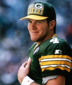 a green bay packers football player wearing a green and yellow uniform with his hands on his chest