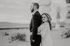 a man and woman standing next to each other in front of some large rock formations