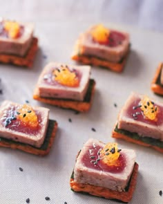 small crackers with various types of food on them sitting on a tablecloth covered surface