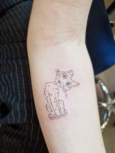 a woman's arm with a small tattoo of two cats sitting on top of each other