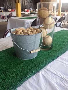 two buckets filled with baseball balls sitting on top of a green carpeted table