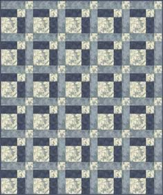 a blue and white quilt with squares on the front, in shades of gray and beige