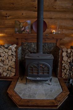 a wood burning stove sitting inside of a living room next to firewood stacked on top of each other