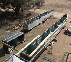 several canoes are lined up on the ground in an area with dirt and trees