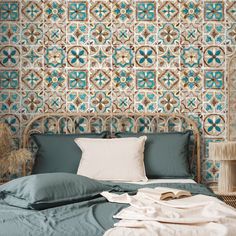 a bed with blue sheets and pillows in front of a wallpapered headboard