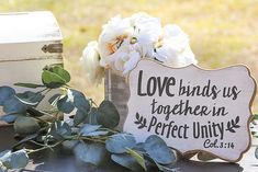 a wooden sign sitting on top of a table next to flowers and an old trunk