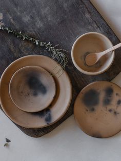 three brown bowls with black spots on them and a wooden spoon in the bowl next to it