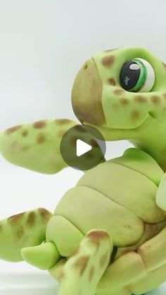 a green toy turtle with brown spots on it's body and arms, sitting in front of a white background