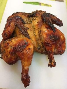 a cooked chicken sitting on top of a white plate next to a pink and yellow background