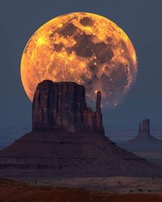 the full moon rises over monument butte in monument national park, utah