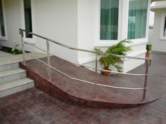 a metal hand rail on the outside of a house with potted plant in front