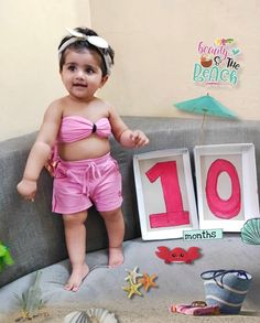 a baby girl standing on top of a couch in front of a sign that says 10 months